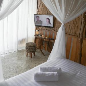 KemadangAma Awa Resort的卧室配有一张床铺,墙上配有电视