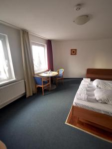 宾茨格兰之酒店的酒店客房配有一张床铺和一张桌子。