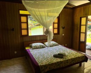 乌图罗阿Te Fare Manulani的一间卧室配有一张床,床的上方是窗帘