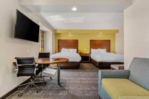 斯汤顿Clarion Pointe Staunton East的酒店客房带两张床、一张桌子和一张沙发