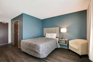 诺克斯维尔WoodSpring Suites Knoxville - Cedar Bluff的一间卧室,卧室内配有一张床和一把椅子