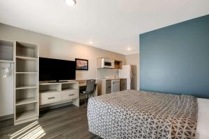 诺克斯维尔WoodSpring Suites Knoxville - Cedar Bluff的一间卧室配有一张床、一张书桌和一台电视