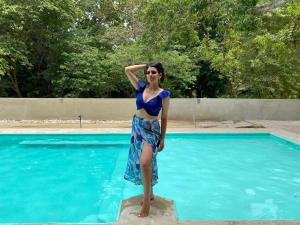 埃尔扎伊诺Tayrona Suites的身着蓝色衣服的女人站在游泳池旁