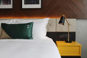 怡保唯裕酒店的一间卧室配有一张带绿色枕头和灯的床