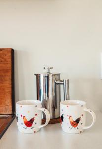 Kaipara FlatsThe Hen House的两个咖啡杯,上面有公鸡的设计
