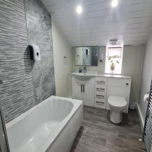 阿尔弗斯顿Ulverston Town Centre Flat (2 Bedrooms)的带浴缸、卫生间和盥洗盆的浴室