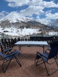 塞斯特雷Monolocale con terrazzo e vista spettacolare sui monti的露台配有一张桌子和两把椅子,露台被雪覆盖着山脉