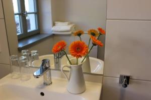 赖因斯贝格St. Laurentius-Blick的浴室水槽上摆放着橙花的花瓶