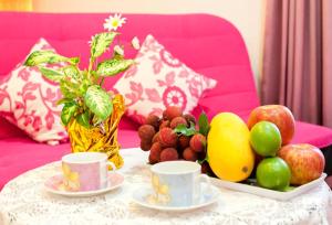 五结自由天地民宿的一张桌子,上面有水果和杯子,放在粉红色的沙发上
