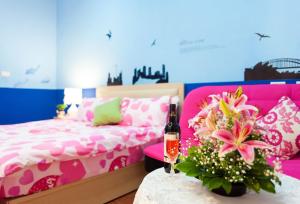 五结自由天地民宿的一间卧室配有粉色床和一张带一瓶葡萄酒的桌子。