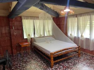 曼巴豪Borbon's Treehouse By the Sea的一间设有床铺的卧室,位于带窗户的房间内