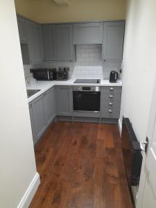 柯库布里Kirkcudbright Holiday Apartments - Apartment E的厨房铺有木地板,配有灰色橱柜。