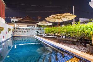暹粒Sihariddh BnB Villa的一个带长椅和遮阳伞的游泳池