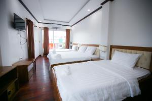 万象Nana Vientiane Hotel的配有电视的酒店客房内的两张床