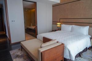 南昌南昌绿地华邑酒店的卧室配有一张白色大床和木制床头板