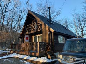 那须町Log village FIKA / Nasu / Woodstove / Starry sky的雪中带前门廊的小房子