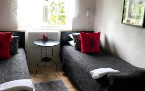 Hammenhög苏德加达奥斯特拉住宿加早餐旅馆的客房配有两张带红色枕头和桌子的床。