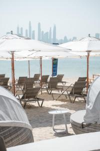 迪拜Wyndham Residences The Palm的海滩上的一组椅子和遮阳伞
