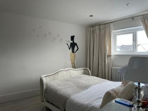 滨海纽比金Coastal Joy - Room 4的卧室配有一张床,墙上挂着一只猫的雕像