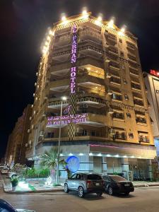 奥朱贝尔Al Farhan Hotel Suites Al siteen的一座大型建筑,前面有汽车停放