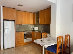 塔拉戈纳Joan XXIII Apartment的厨房配有桌子和白色冰箱。