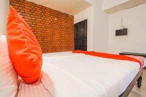 ChicolnaOYO La Petite Near Dabolim Airport的一间卧室配有一张带橙色枕头的床