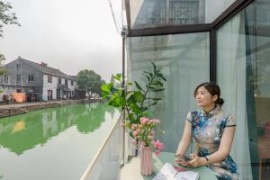 苏州Tongli Slowlife River View Inn的坐在河边窗台上的女人