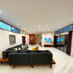 克里比Villa 4 Chambres avec piscine sur Kribi的客厅配有黑色沙发和平面电视。