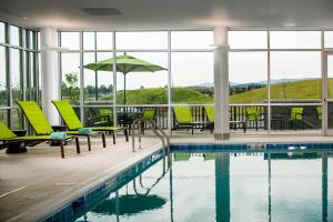 卡利斯佩尔SpringHill Suites by Marriott Kalispell的一个带椅子和桌子的游泳池以及一把遮阳伞
