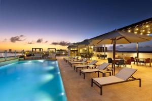 坎昆Residence Inn by Marriott Cancun Hotel Zone的一座设有游泳池、椅子和桌子的酒店