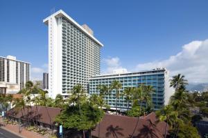 檀香山喜来登凯拉尼公主酒店的一座高大的白色建筑,前面有棕榈树