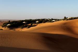 Murquab迪拜阿玛哈豪华精选沙漠水疗度假酒店的沙漠,有沙丘和远处的房屋