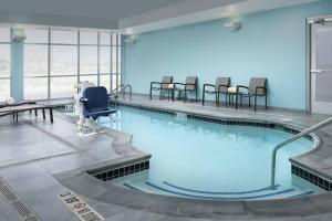 温莎SpringHill Suites by Marriott Loveland Fort Collins/Windsor的大楼内带椅子的大型游泳池