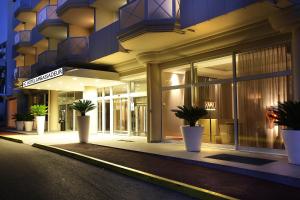 胡安莱潘安提布 - 瑞昂莱潘大使万豪AC酒店的一座在晚上在前面有盆栽植物的建筑