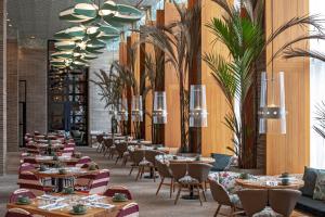 巴兰基亚Barranquilla Marriott Hotel的一间设有桌椅的餐厅,种植了棕榈树