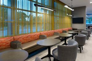 莱克兰SpringHill Suites Lakeland的一间设有桌椅和大窗户的等候室
