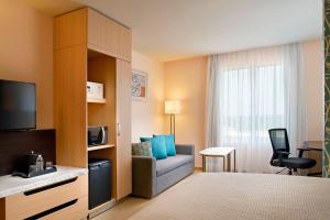 比亚埃尔莫萨塔巴斯科维拉埃尔莫萨万豪费尔菲尔德客栈及套房的酒店客房配有一张床、一把椅子和一台电视。