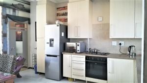 SandtonLonehill的厨房配有白色橱柜和冰箱。