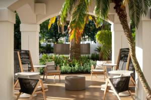 棕榈滩花园棕榈滩花园万豪酒店的庭院配有桌椅和棕榈树