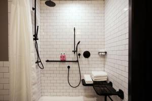 里士满Moxy Richmond Downtown的带淋浴和长凳的白色瓷砖浴室