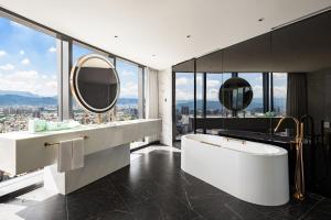 台中市台中李方艾美酒店的一间带大型白色浴缸和镜子的浴室