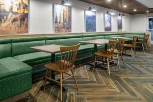 落基山Fairfield Inn & Suites Rocky Mount的餐厅设有绿色的展位和木桌及椅子
