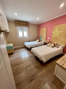科巴罗La casita de Ouriceira的配有粉红色墙壁和木地板的客房内的两张床