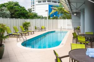 迈阿密迈阿密市中心/医疗中心春季山丘套房酒店的一座带桌椅的游泳池位于大楼旁