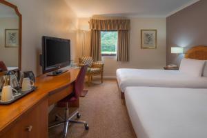 米尔顿凯恩斯Delta Hotels by Marriott Milton Keynes的酒店客房配有一张床和一张书桌及一台电视