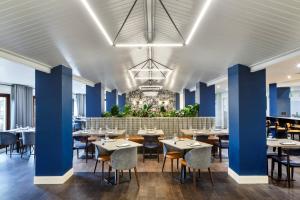 米尔顿凯恩斯Delta Hotels by Marriott Milton Keynes的餐厅拥有蓝色的墙壁和桌椅