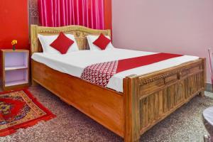 巴特那OYO Flagship Hotel Kashyap Heritage的一间卧室配有一张带红色枕头的大型木制床。