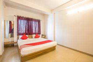KharadiOYO Primrose Regency Near Amanora Mall的一间卧室配有一张带红色枕头的床和一扇窗户