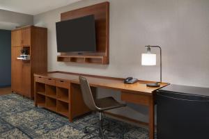 加蒂诺Four Points by Sheraton Hotel & Conference Centre Gatineau-Ottawa的酒店客房设有一张带显示器和椅子的桌子