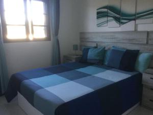 查德尔帕罗奥Natural y sano: Charco del Palo的窗户客房内的一张蓝色和白色的床